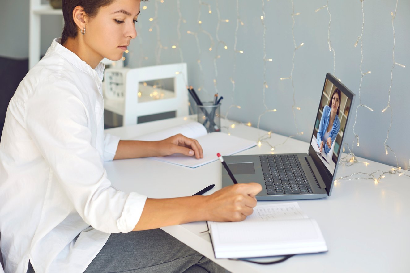 Young Woman Taking Notes during Online Consultation with Coach or Video Lesson with Teacher